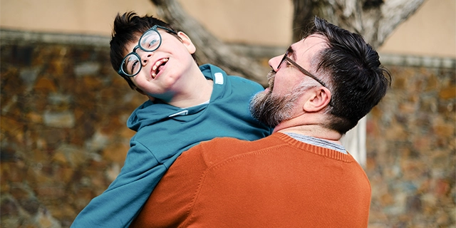 Father holding laughing child with disability