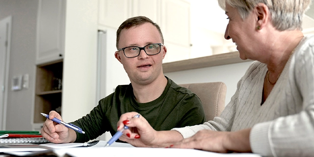 Woman assisting a male with Down syndrome